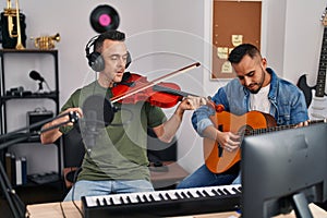 Two men musicians playing classical guitar and violin at music studio