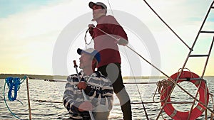 Two men navigating yacht at sunset, friendship, sailing, sport