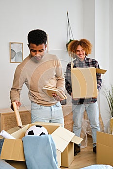 Two men packing in a moving cardboard box to settle in a new home.