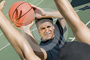 Two men playing basketball on a sunny day