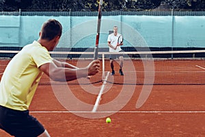 Two men playing tennis on clay tennis field