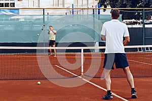 Two men playing tennis on clay tennis field