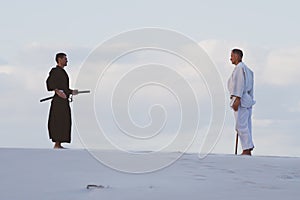 Two men practicing Japanese martial arts in desert