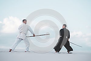 Two men practicing Japanese martial arts in desert