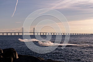 Two men racing on jetskis in the cold ocean in front of the Oresund bridge on a summer evening