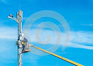 Two men, raised on a crane, will repair the power line support against the blue sky. Dangerous profession, selective focus