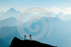 Two Men reaching summit after climbing and hiking enjoying freedom and looking towards mountains silhouettes panorama