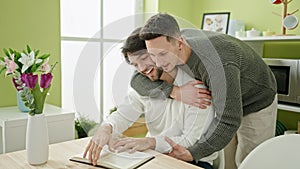 Two men reading book sitting on table at dinning room