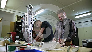 Two men repair the robot in the workshop