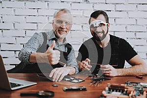Two Men Repairing Mobile Phone in Modern Workshop