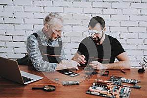 Two Men Repairing Mobile Phone in Modern Workshop.