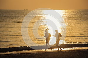 Two men running with bare feet on beach