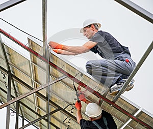 Male workers mounting solar panel system outdoors.