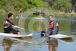 two men sat on paddle boards on lake