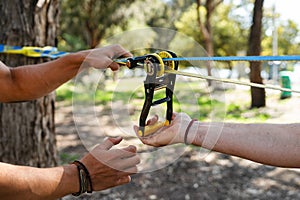 Two men setting up slacklining equipment in city park during summer day