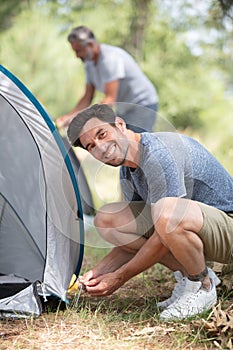 two men setting up tent for camping in nature