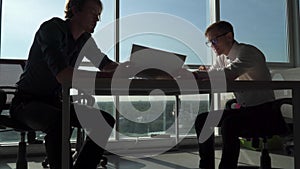 Two men shake hands at the table in the office