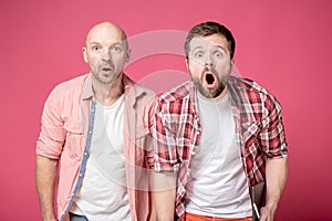 Two men are shocked, they open their mouths in amazement and look at the camera with big eyes, with interesting excited