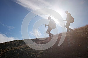 Two men silhouettes walking along the top of the mountain