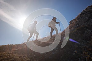 Two men silhouettes walking along the top of the mountain