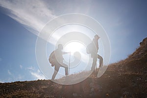 Two men silhouettes walking along the top of the mountain