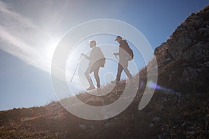 Two men silhouettes walking along the top of the mountain