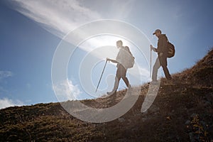 Two men silhouettes walking along the top of the mountain