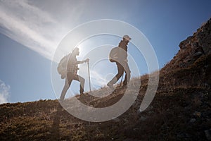 Two men silhouettes walking along the top of the mountain