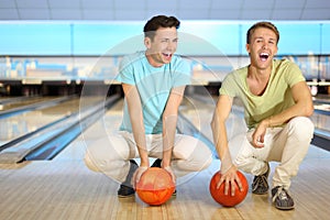 Two men sit on floor with balls in bowling club