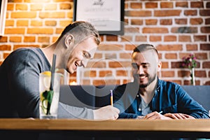 Two men sitting in a restaurant and laughing.