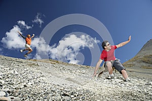 Two Men Sliding Down Scree Field