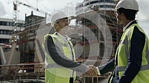 Two men standing on construction site and shaking hands