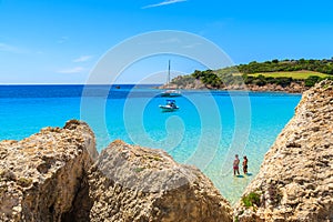 Two men standing in sea water on beautiful beachTwo unidentified men standing in azure water of Grande Sperone bay and looking at