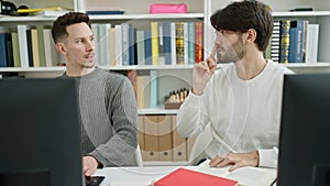 Two men students using computer studying at library university