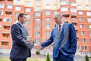 Two men in suits with clipboard and keys negotiate