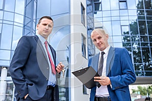 Two men in suits with clipboard and keys negotiate photo