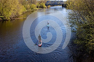 Two men are swimming on a paddleboard on the spring river.I can`t see his face