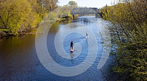 Two men are swimming on a paddleboard on the spring river.I can`t see his face