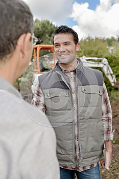 Two men talking digger in background