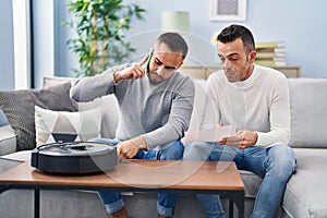 Two men talking on smartphone with technician vacuum robot service at home