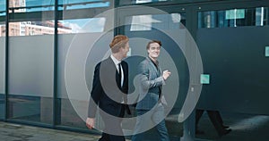 Two men top managers workers discussing business plans walking outdoors along office building. Businessmen in formal