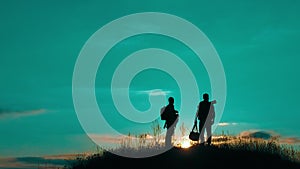 Two men tourists night hikers silhouette go to the mountains sunset travel slow motion video. Traveler successful young