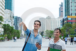 Two men tourists smile point finger sightseeing