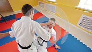 Two men training their aikido skills. Training their fighting. Protecting from a leg hit and throwing the opponent on