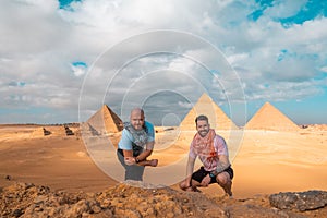 Two men travelers posing in front of the great pyramids of giza in cairo egypt. Traveling egypt during the winter, cold winter