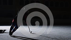 Two men in uniforms and helmets with hockey sticks skate on ice arena. One player pushes another, dribbles and hitting