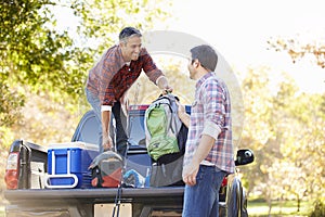 Two Men Unpacking Pick Up Truck On Camping Holiday