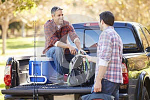 Two Men Unpacking Pick Up Truck On Camping Holiday