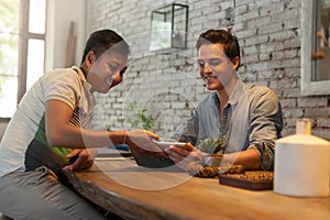 Two Men Using Tablet Computer at Table Cafe