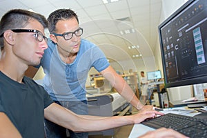 Two men wearing eyeglasses looking at computer screen